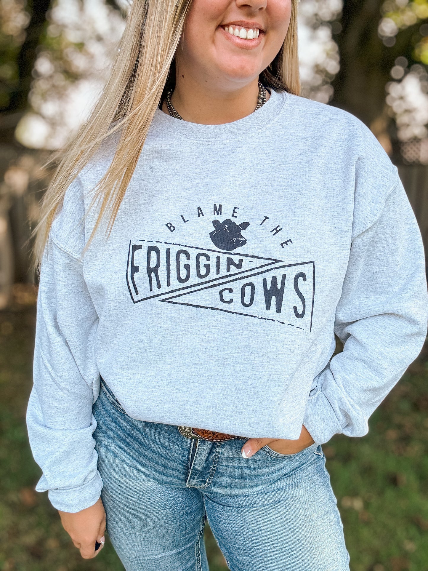 Side view of the Blame the Cows Crewneck showing western graphic and relaxed fit, styled with light wash denim.
