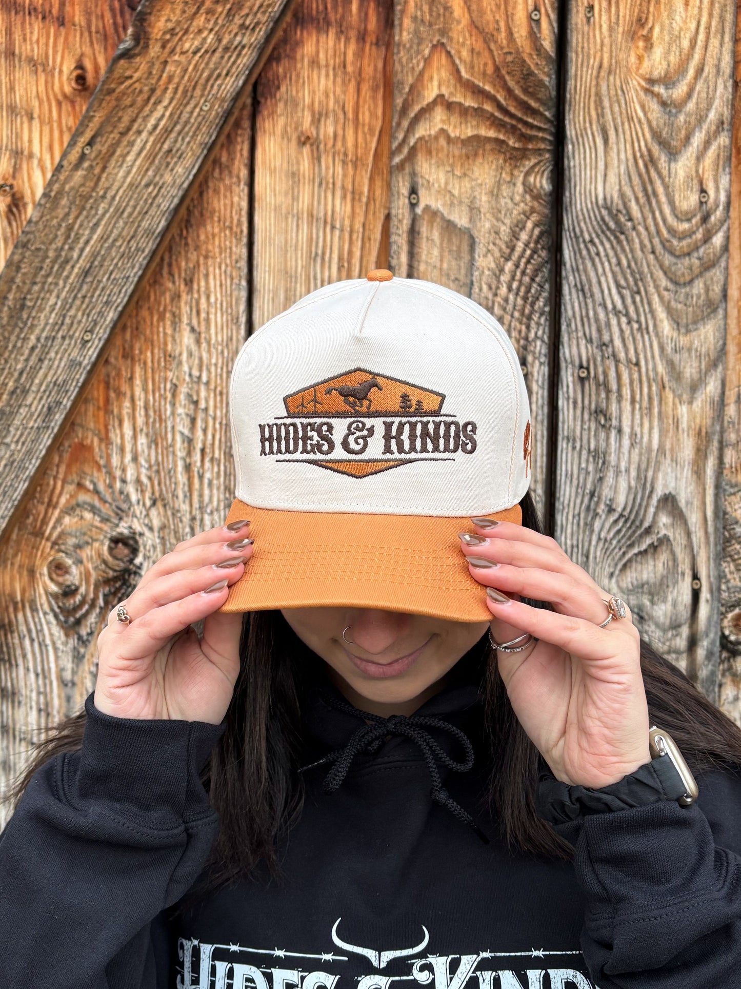Angled front view of tan and cream Hides & Kinds Houston Hat highlighting embroidered desert logo patch.