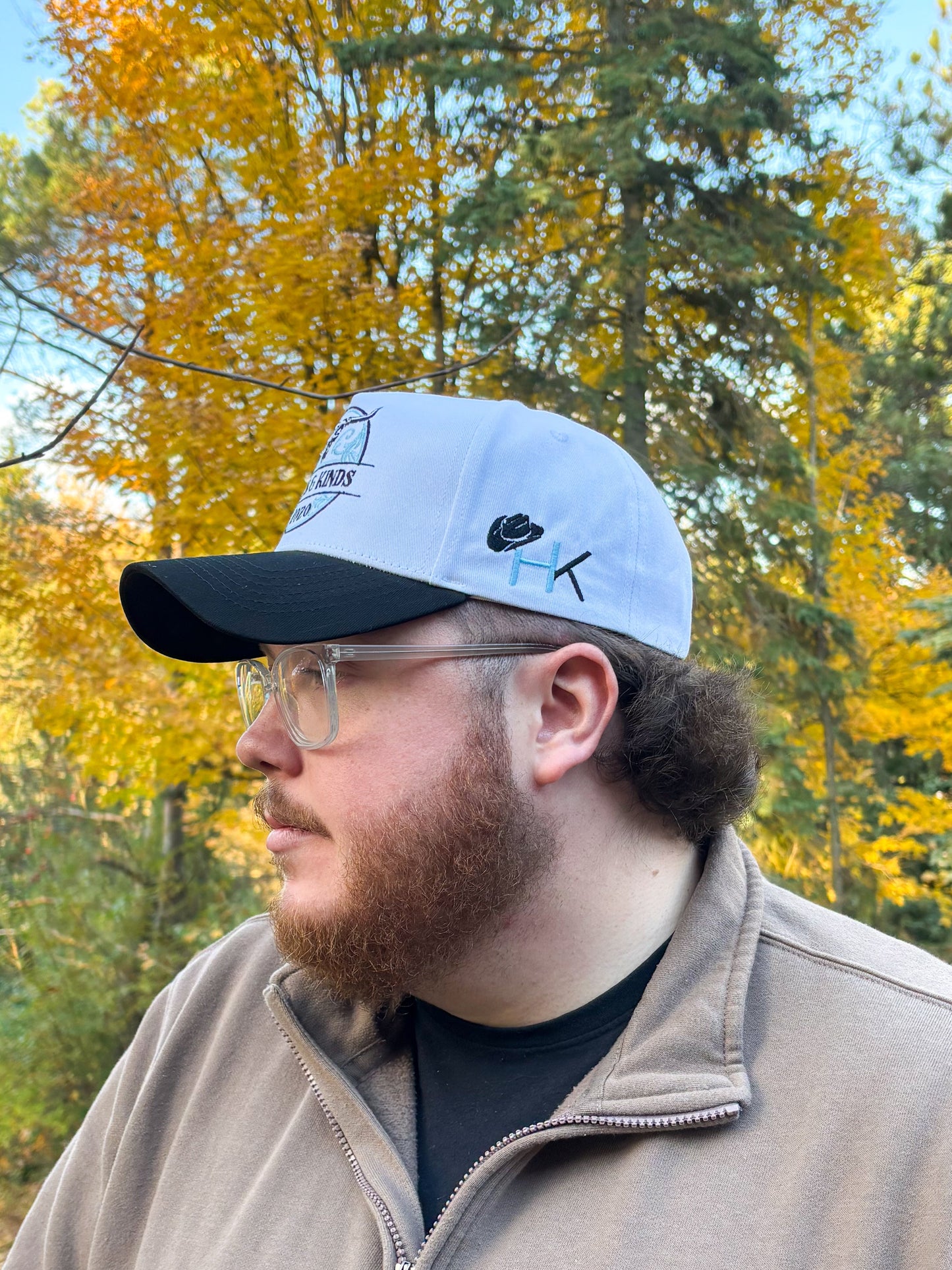 Side profile of teal and black Hides & Kinds Stampede Snapback styled on male model with HK side logo.
