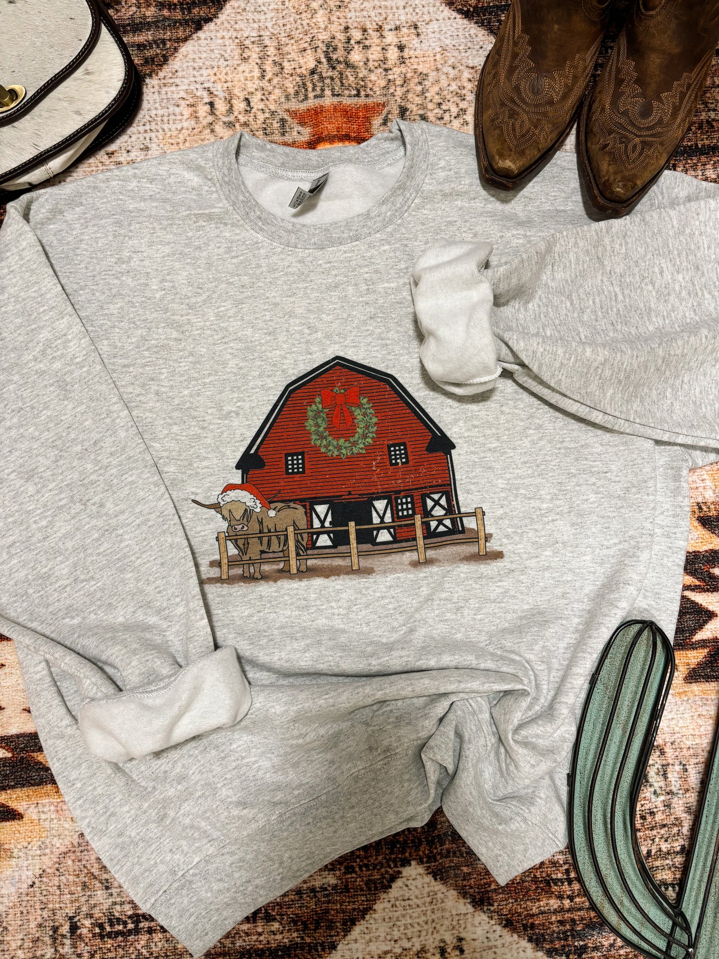 Close up of holiday barn and longhorn design on grey western crewneck