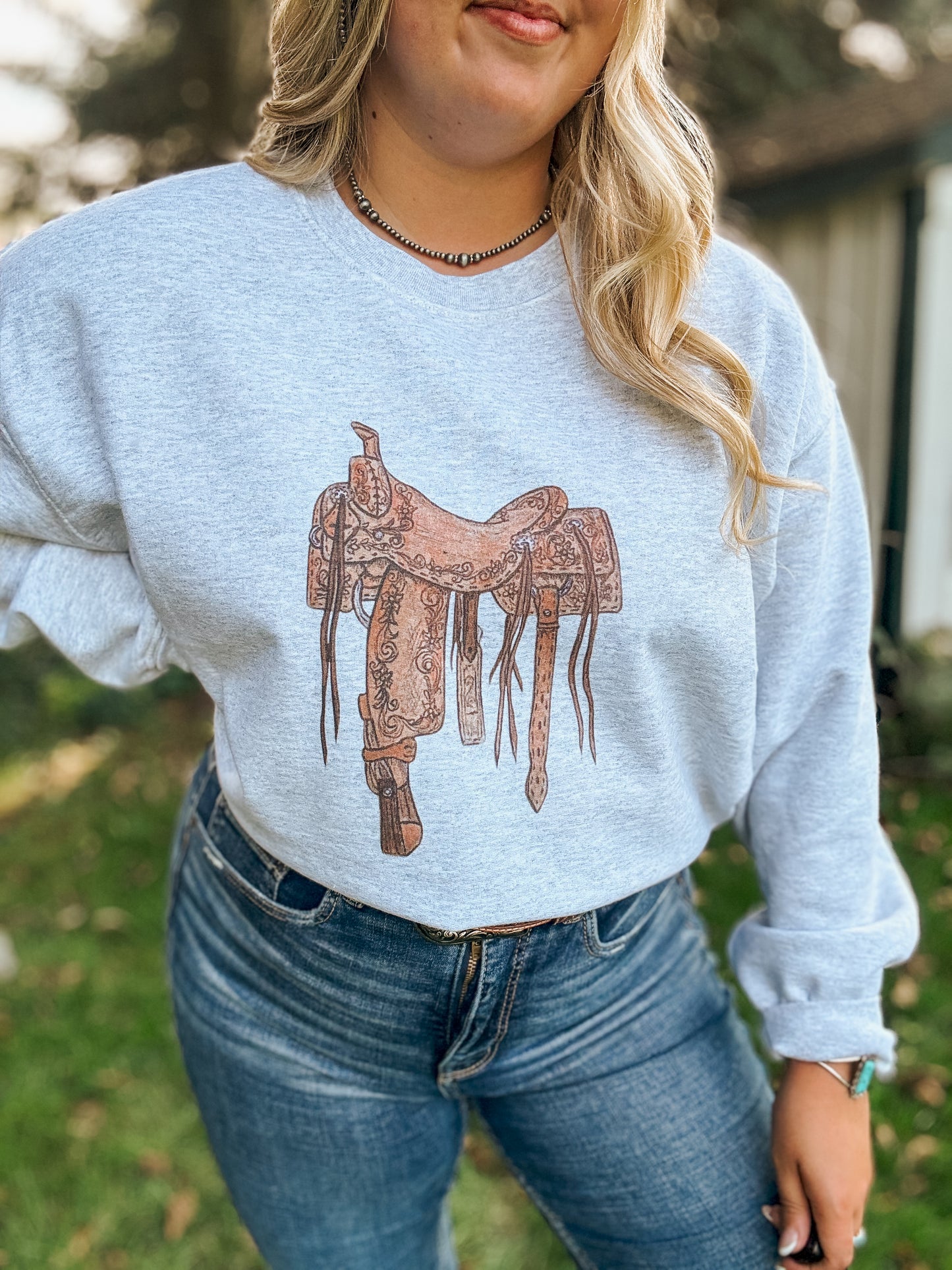 Detailed shot of the Saddle Up Crewneck highlighting the vintage western saddle illustration on the chest.