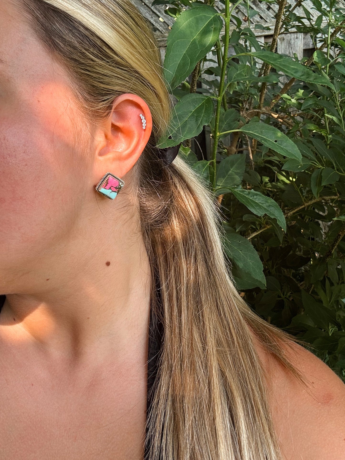 Close-up of cotton candy turquoise diamond shaped stud earrings in hand