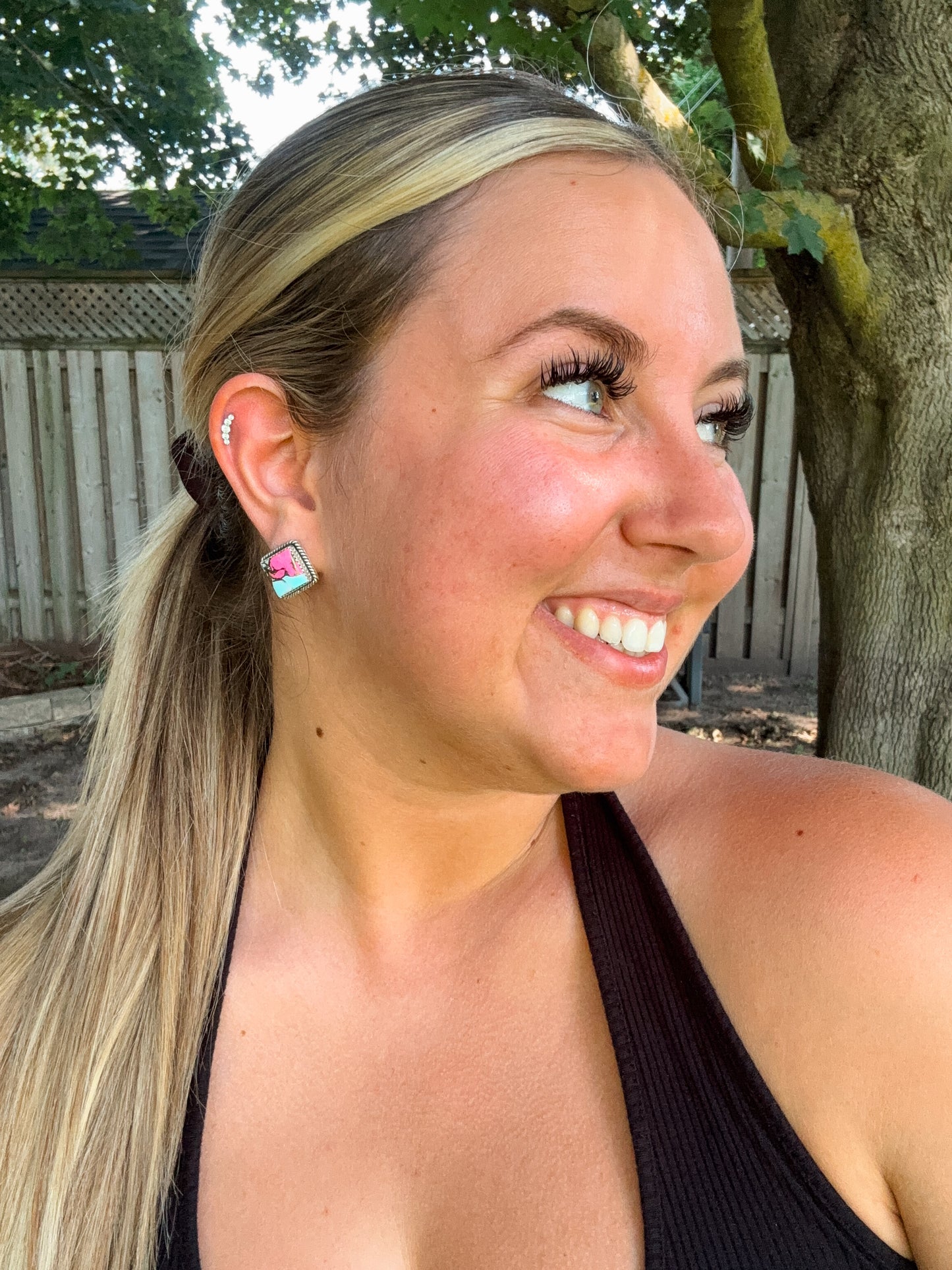 Woman smiling while wearing cotton candy turquoise diamond stud earrings