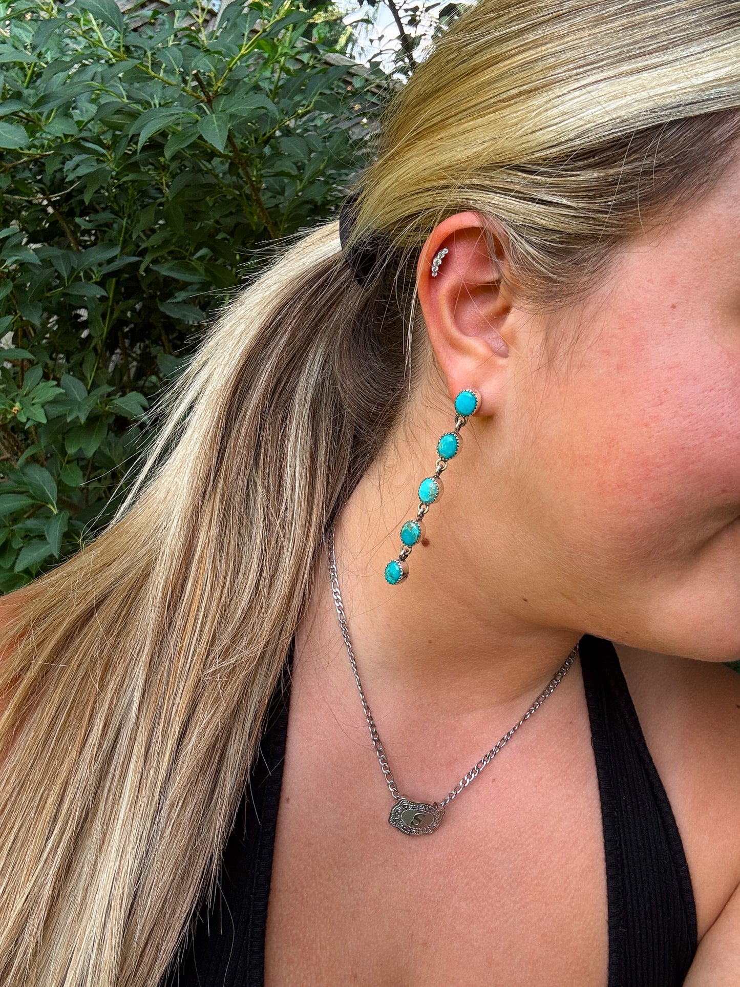 Close up of Cowgirl Cascade turquoise drop earrings on model