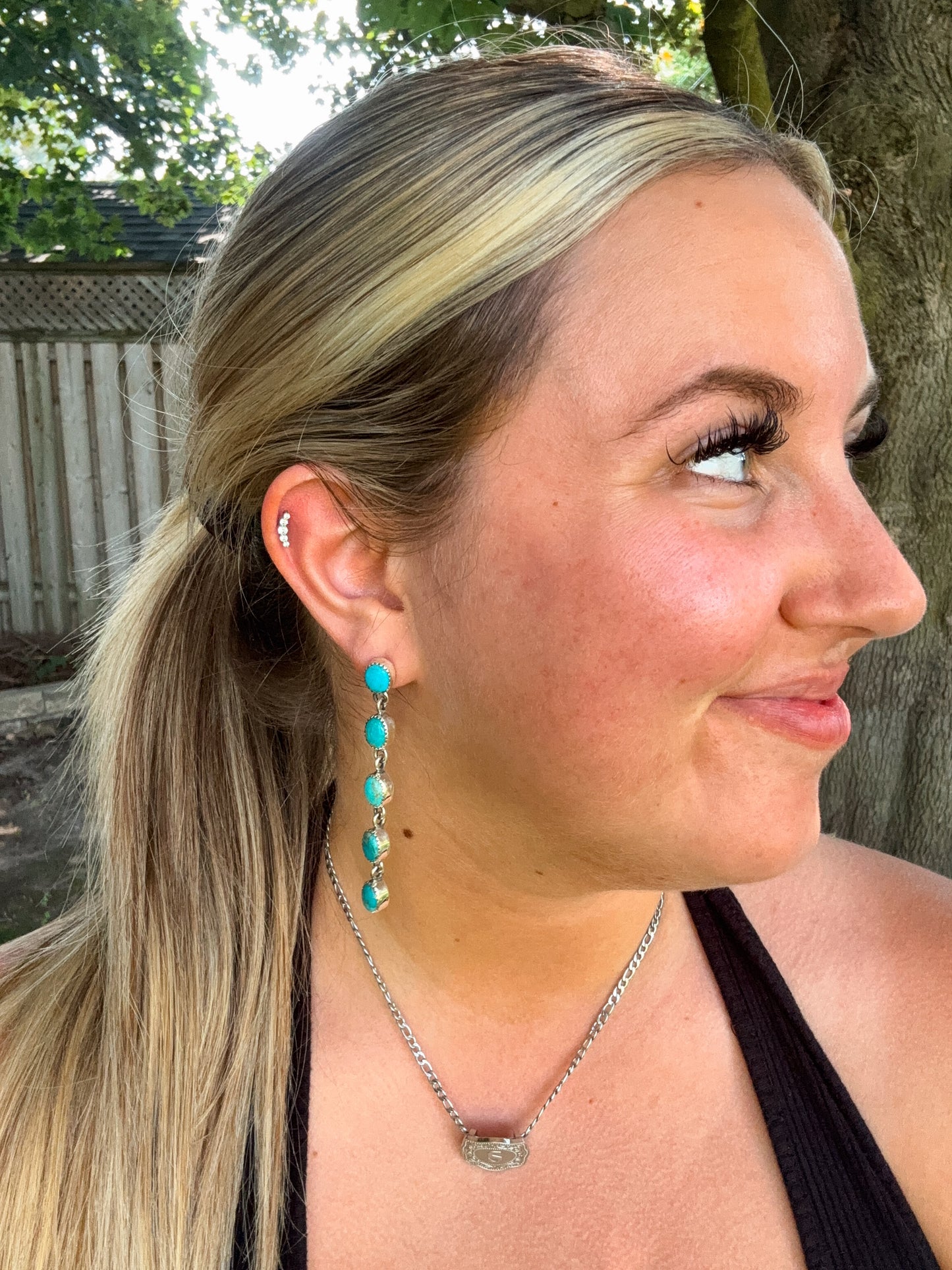 Cowgirl Cascade turquoise drop earrings worn outdoors in natural light with black tank and silver necklace
