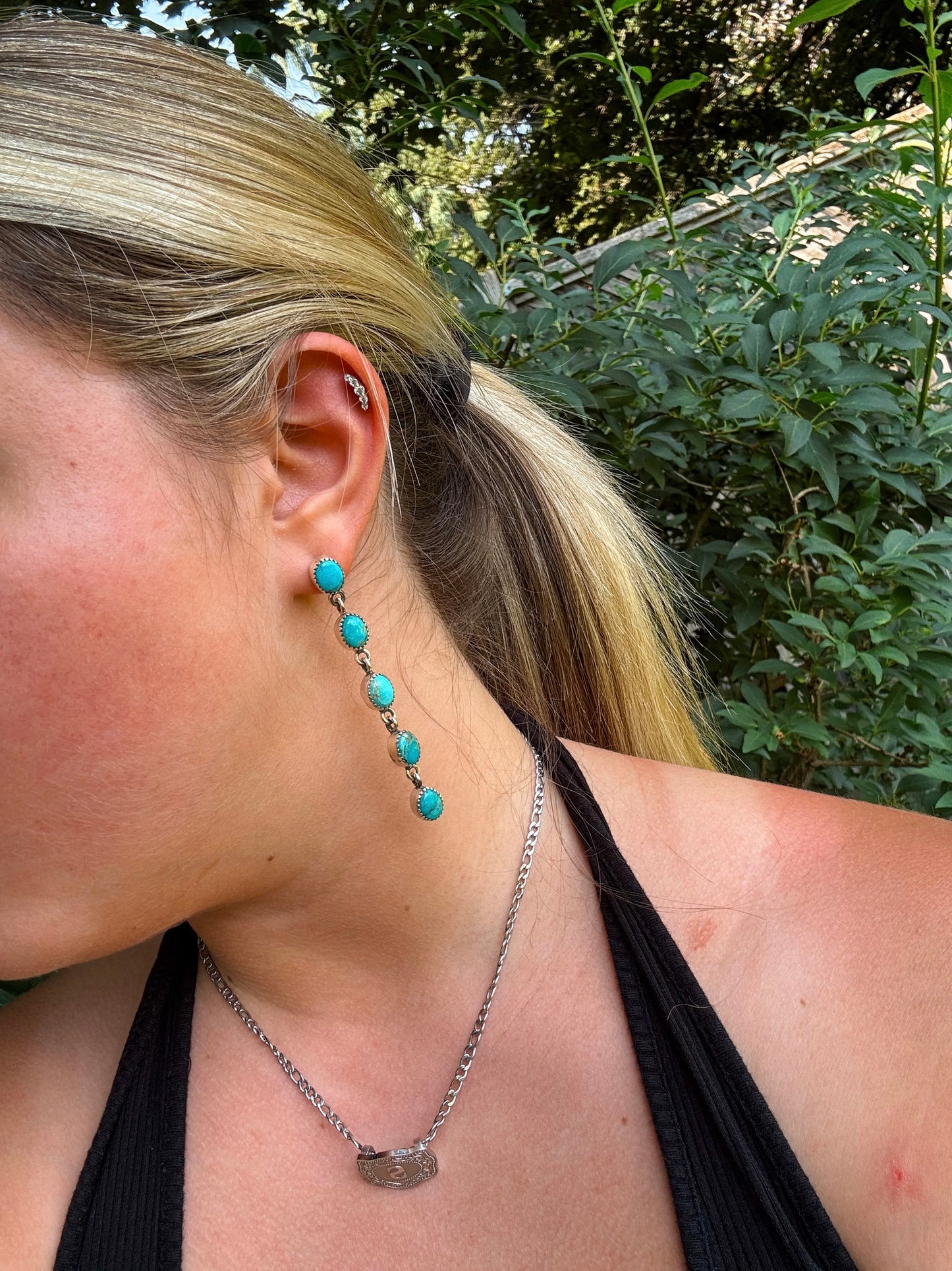 Side profile of model wearing long H&K turquoise drop earrings