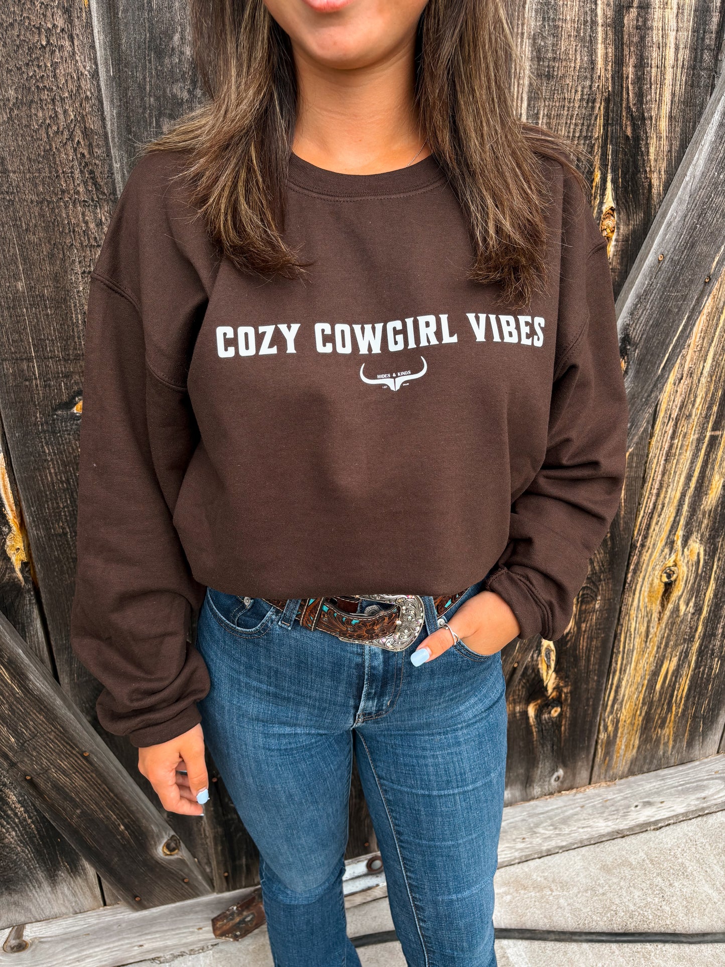 Close up of model wearing the Cozy Cowgirl Vibes Crewneck in chocolate brown from Hides & Kinds