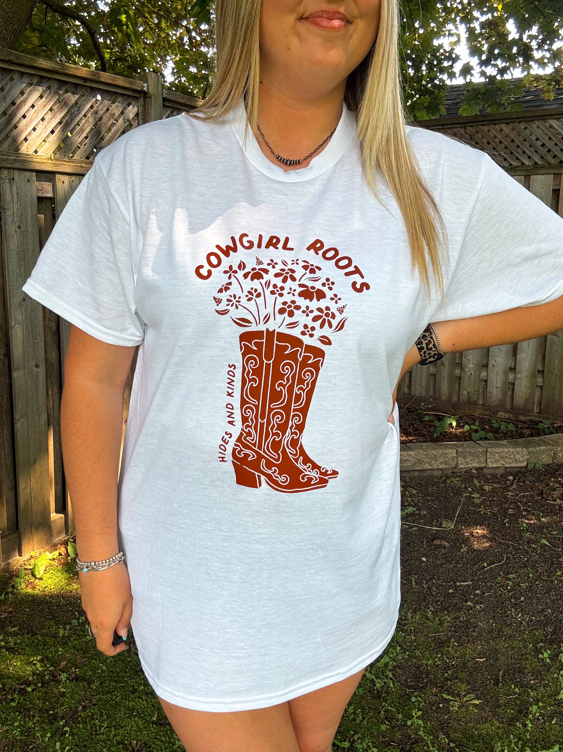 Close up of Cowgirl Roots tee featuring red floral cowboy boot graphic and Hides and Kinds branding.