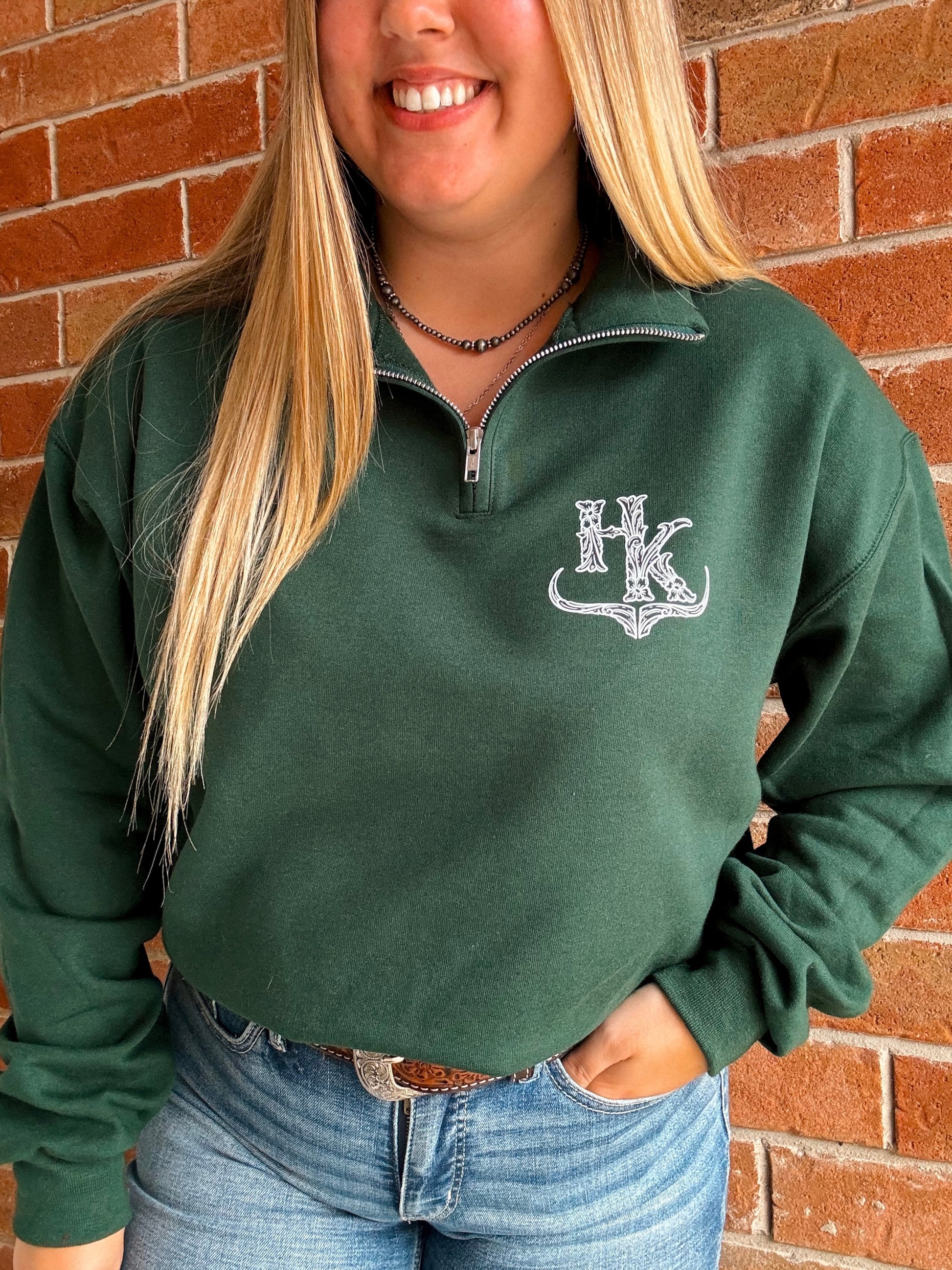 HK Branded forest green quarter zip styled with jeans, featuring detailed bullhorn chest design.
