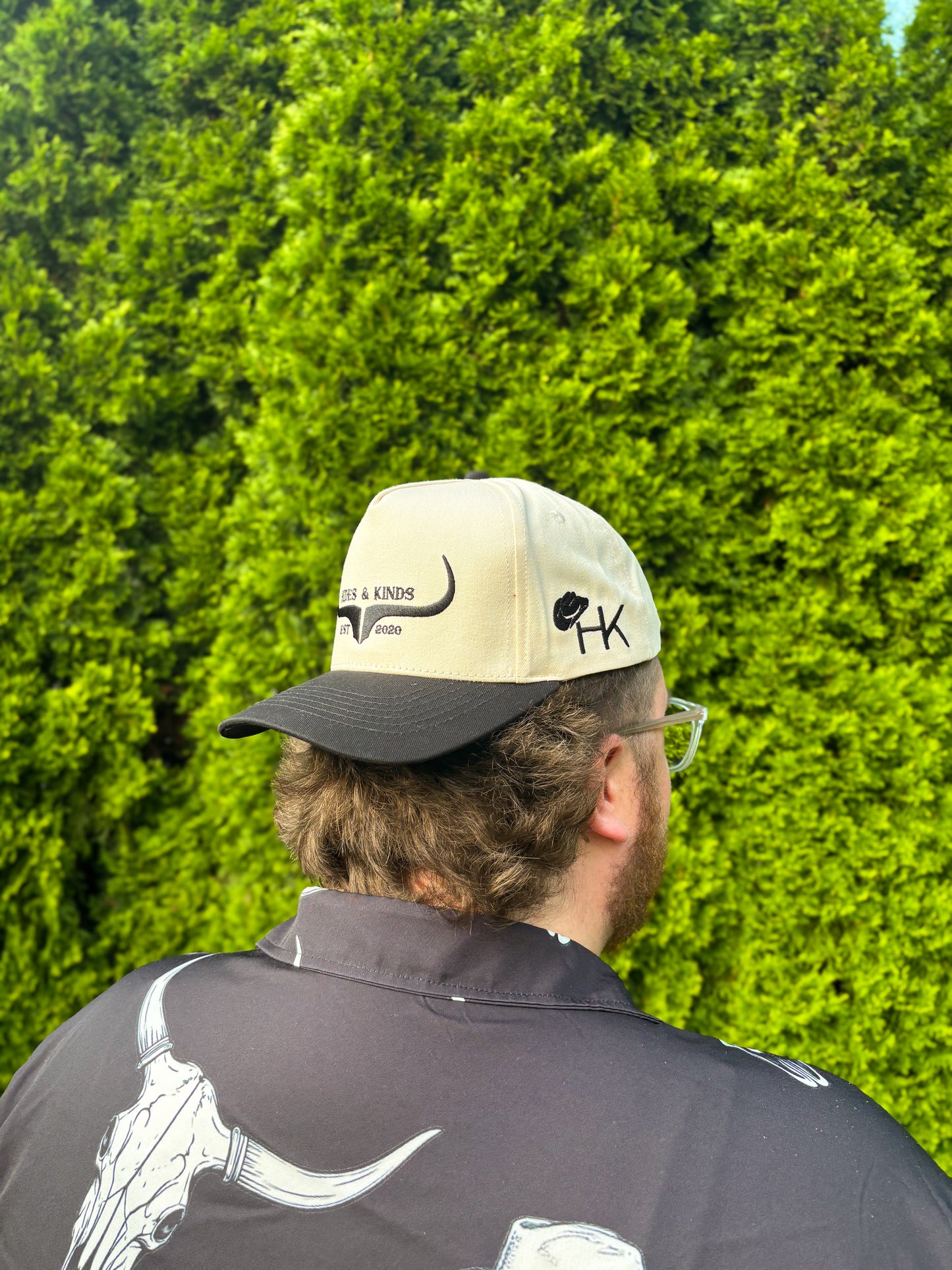 Side angle of man in Hides & Kinds original logo hat, showing HK cowboy hat embroidery and black brim detail.