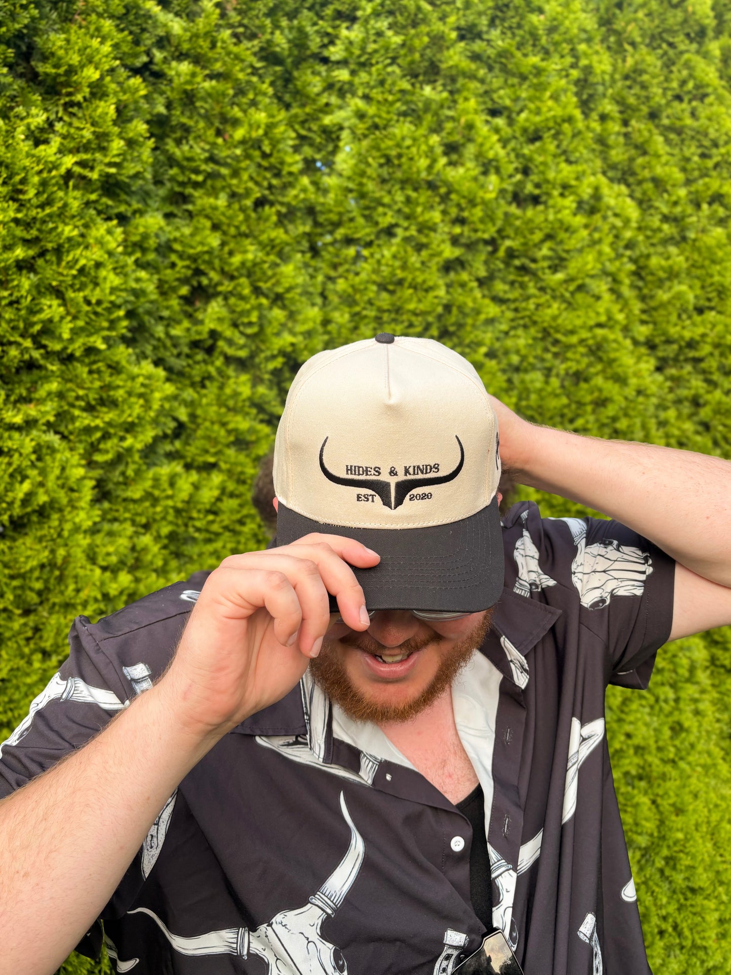 Woman modeling the Hides & Kinds western snapback hat in black and natural with hands on brim, styled with casual western wear.