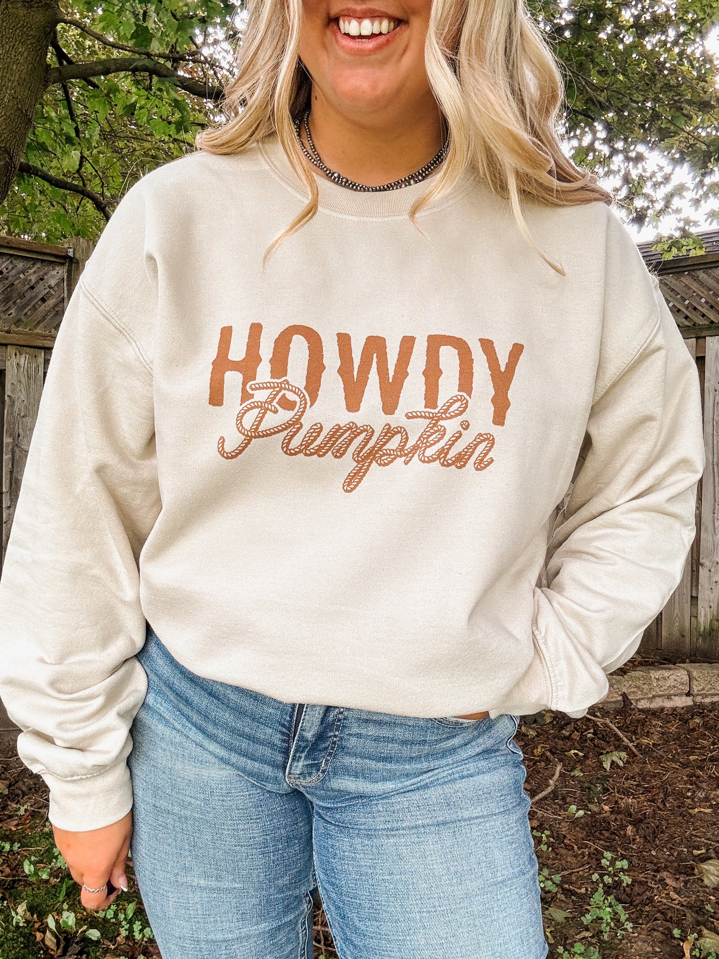 Close up of Howdy Pumpkin text design on beige crewneck with a western style rope font.