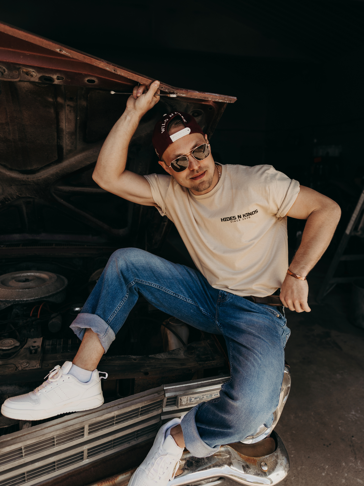 Model wearing the Hides & Kinds Long Haul Tee while sitting on a vintage truck, showcasing the men's country lifestyle tee.