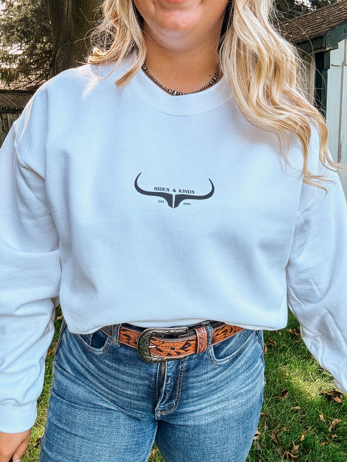 Woman wearing the Original Logo Crew in white with Hides & Kinds longhorn logo graphic on the chest.