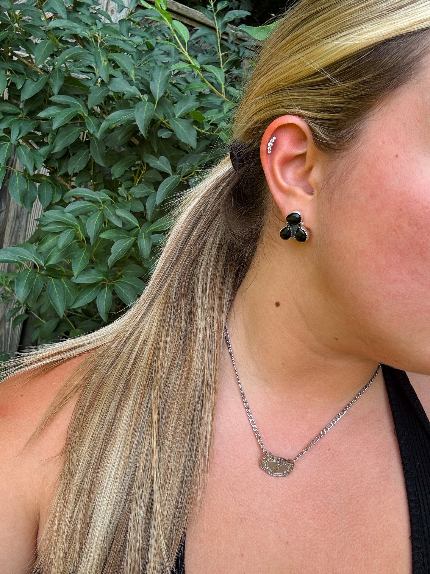 Close-up of Triple Stone Stud earrings in black onyx on model