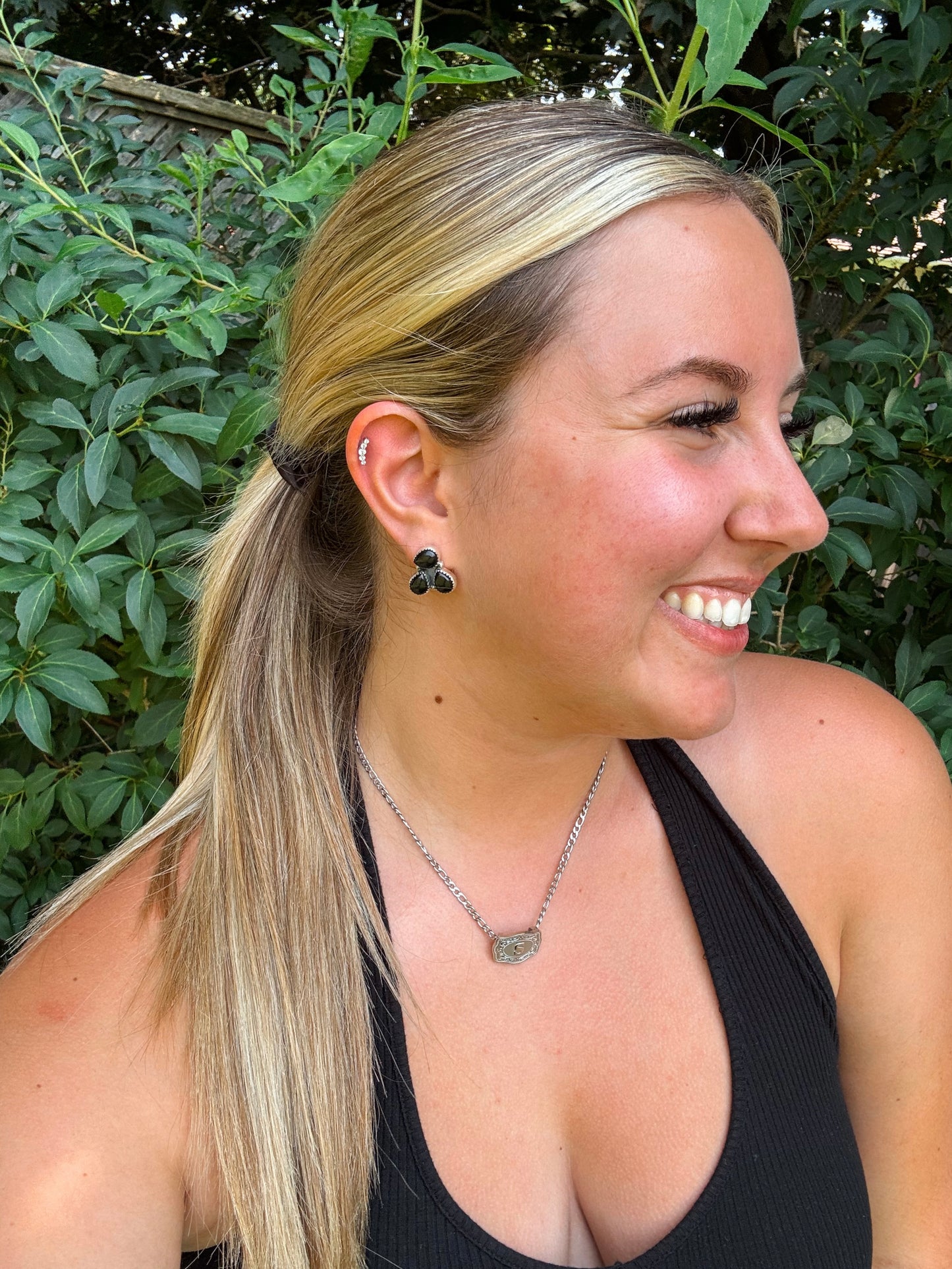 Model wearing black onyx Triple Stone Studs with side profile smile
