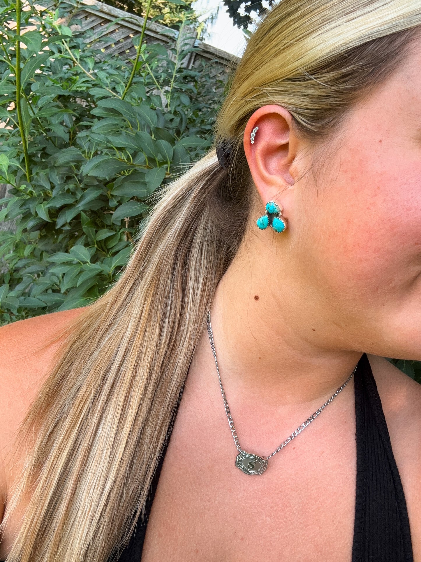 Side profile view of turquoise Triple Stone Stud Earrings with silver necklace and ponytail hairstyle