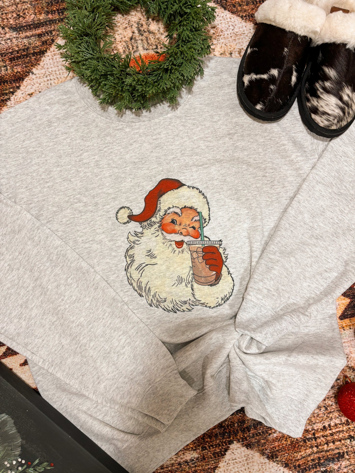 Vintage Santa iced coffee crewneck from Hides & Kinds, laid out with cozy Christmas accents