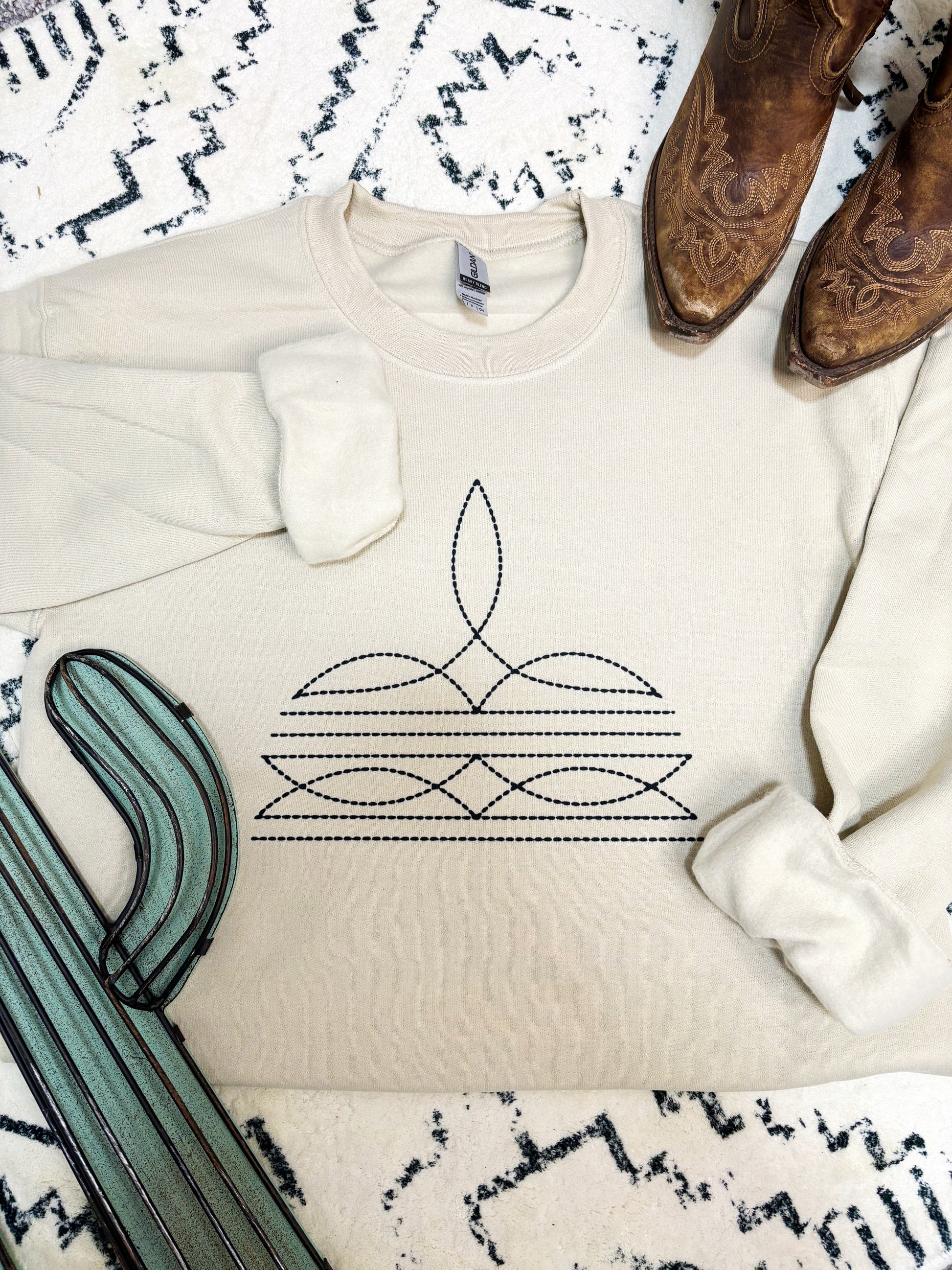 Sand colored crewneck with stitched cowboy boots graphic, styled with warm toned western pieces