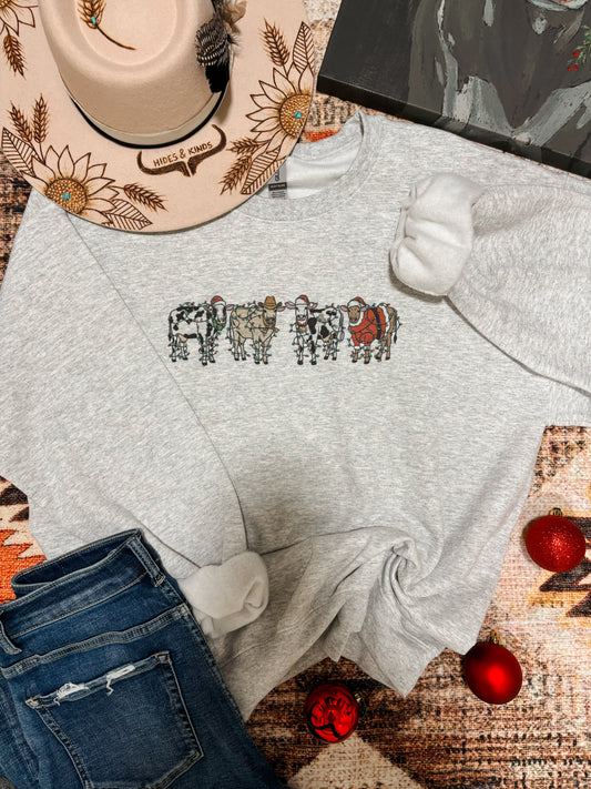 Heather grey Christmas cow graphic crewneck laid flat with holiday decor and jeans