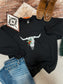 Western Christmas sweatshirt with a festive skull design, laid out beside cowboy boots, jeans, and a Southwestern boho print card.