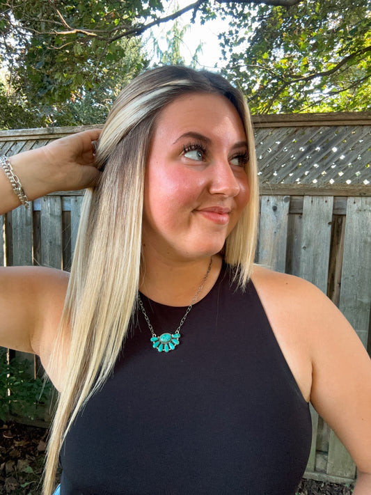 Western turquoise necklace styled on a smiling woman with long blonde hair and a black tank top