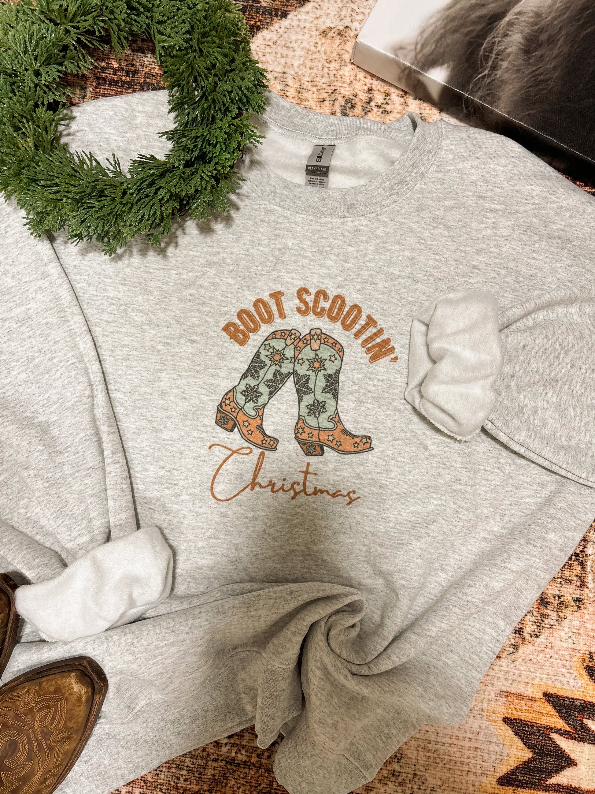 Close up of Boot Scootin’ Christmas graphic on grey western crewneck by Hides & Kinds
