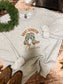 Christmas cowgirl sweatshirt with boot graphic and wreath accent, laid flat on western rug