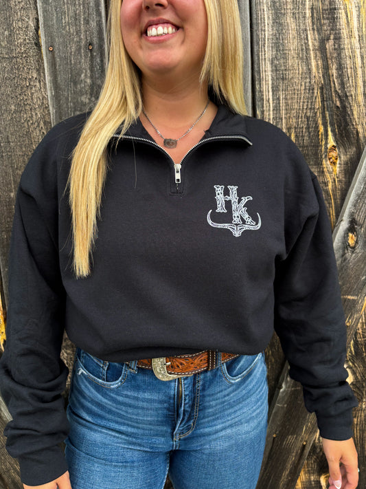 Close up of a woman wearing the Hides & Kinds black brand quarter zip with white logo design