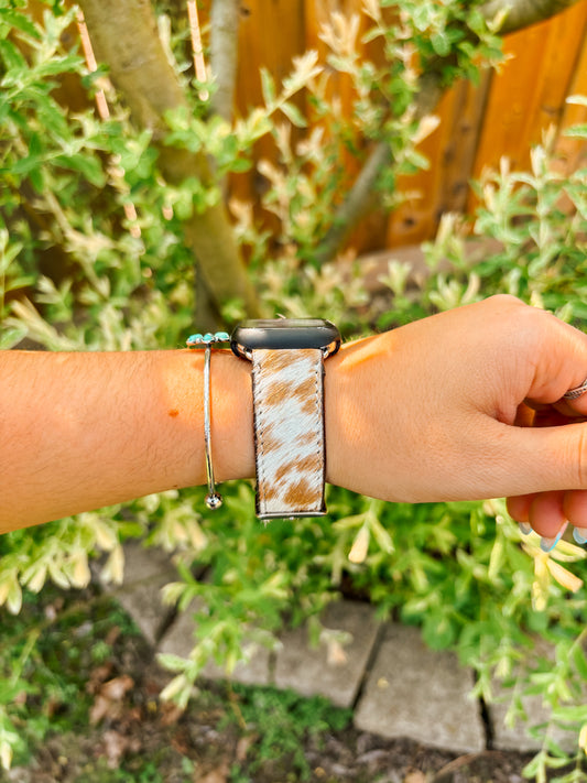 Brown and white cowhide Apple Watch band shown on wrist, front view