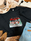 Close up flat lay of black Budweiser Christmas crewneck with Clydesdale horse graphic and rustic western holiday styling.