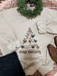 Cream crewneck with Christmas chicken tree design, styled with a green garland, black jeans, and cowboy boots on a western rug