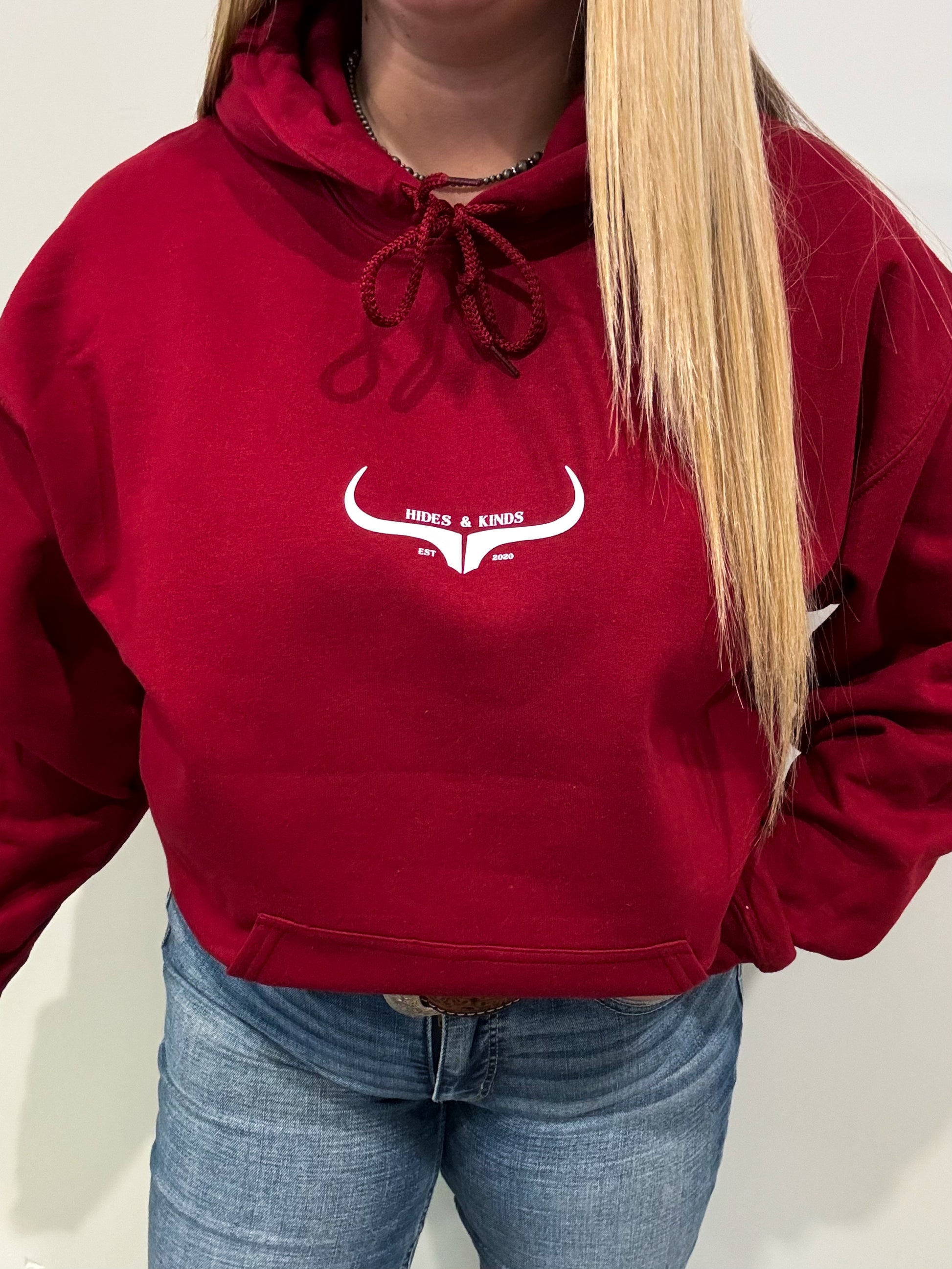 Full body view of woman in Hides & Kinds garnet red hoodie with longhorn logo