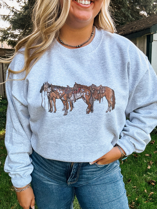 Model wearing Ranch Horse Crewneck in ash grey featuring saddled horse graphic, styled with denim for a casual country look