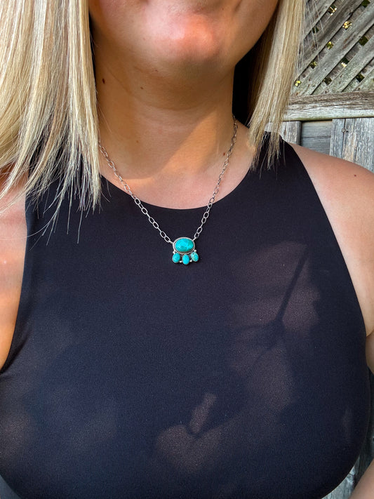 Close up of Saddle Rock Necklace with large turquoise centerpiece and three dangle stones on silver chain