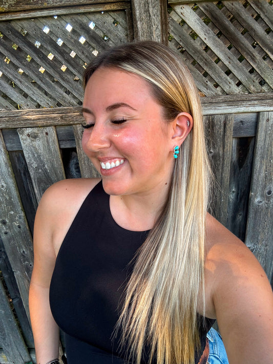 Smiling woman wearing turquoise Stone Row Studs with long blonde hair and black tank