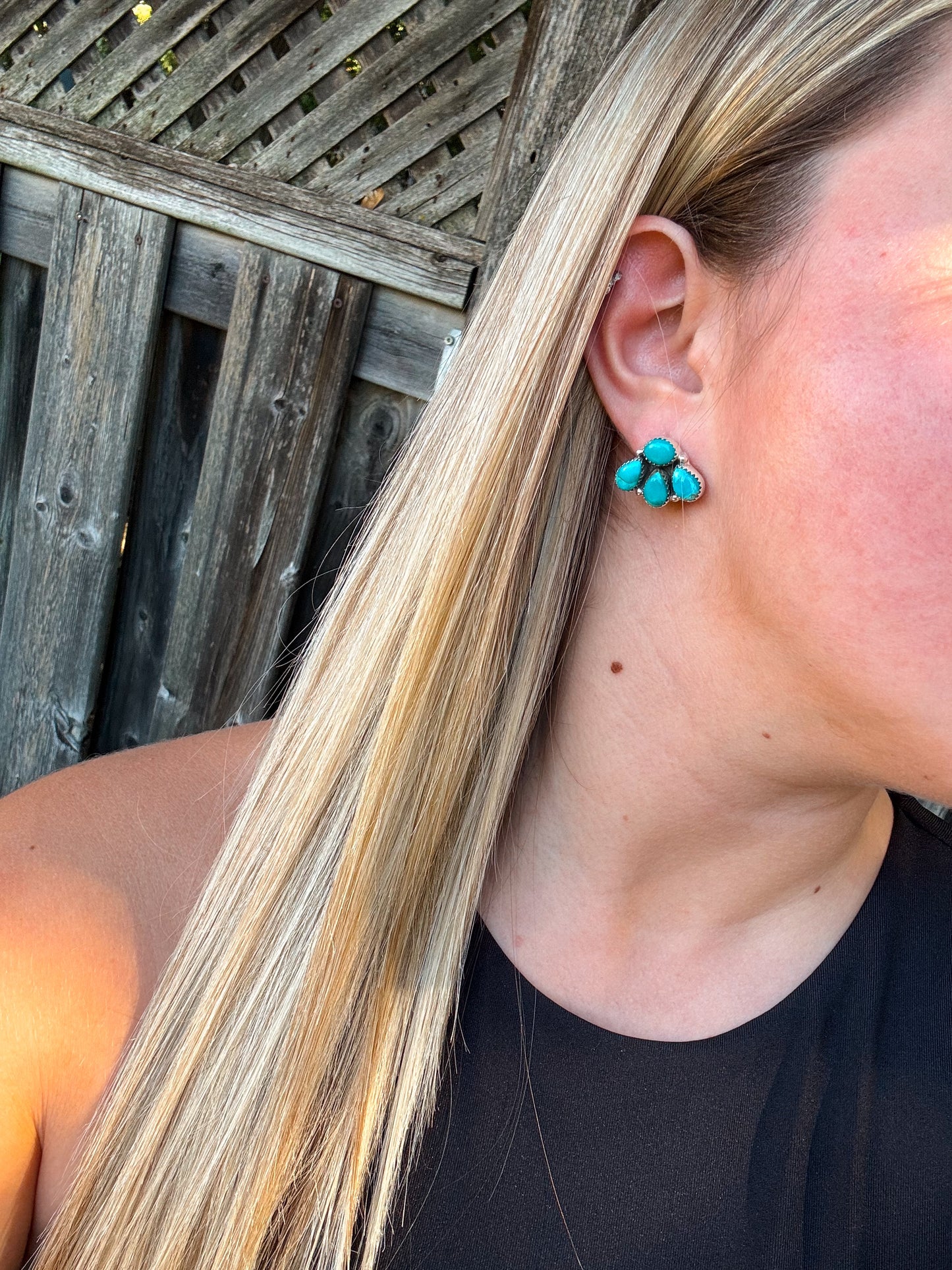 Side profile of turquoise stud earrings being worn with hair tucked behind ear