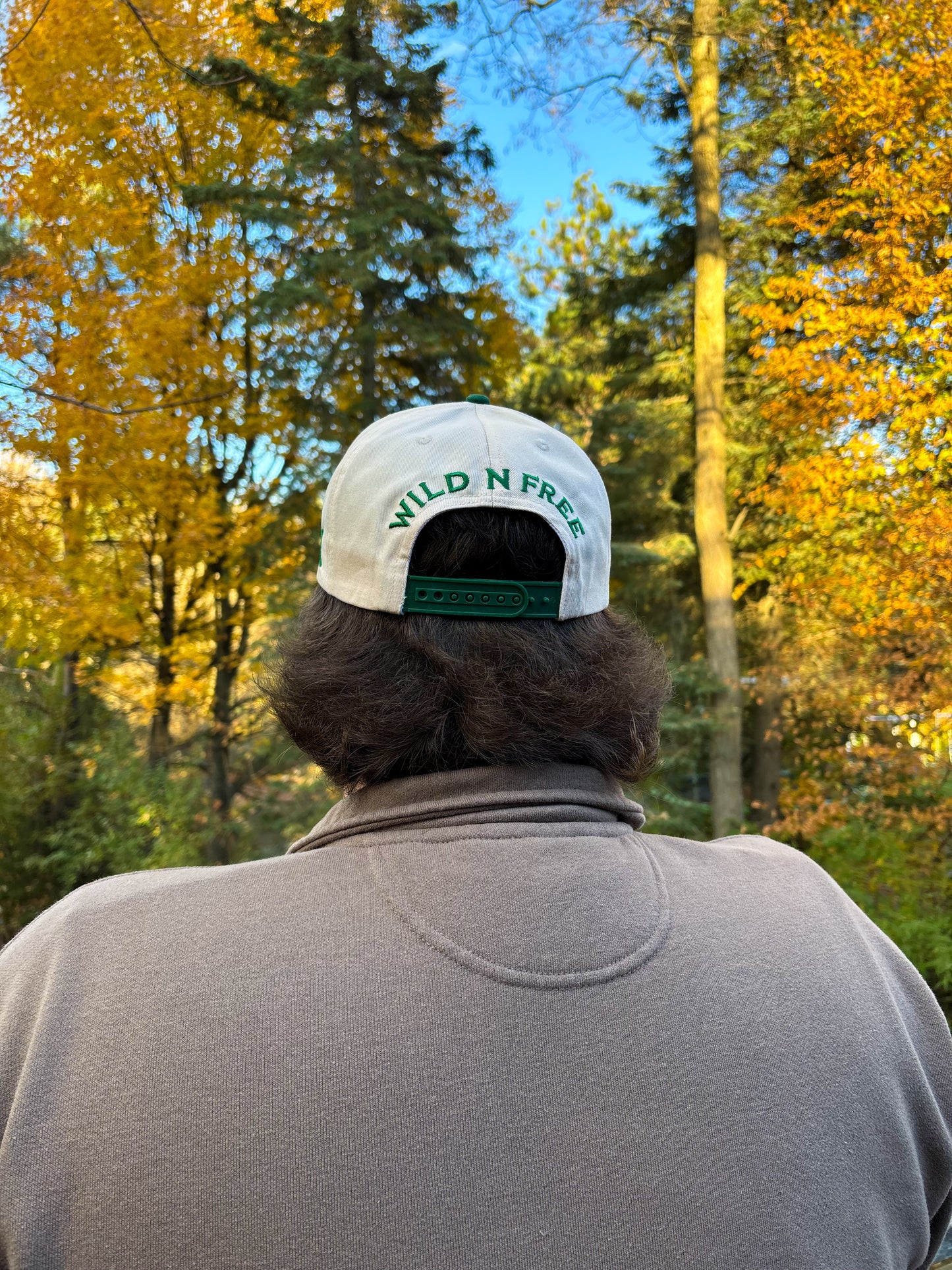 Back view of The Country Line Hat in green and cream with Wild N Free embroidery above snapback closure.
