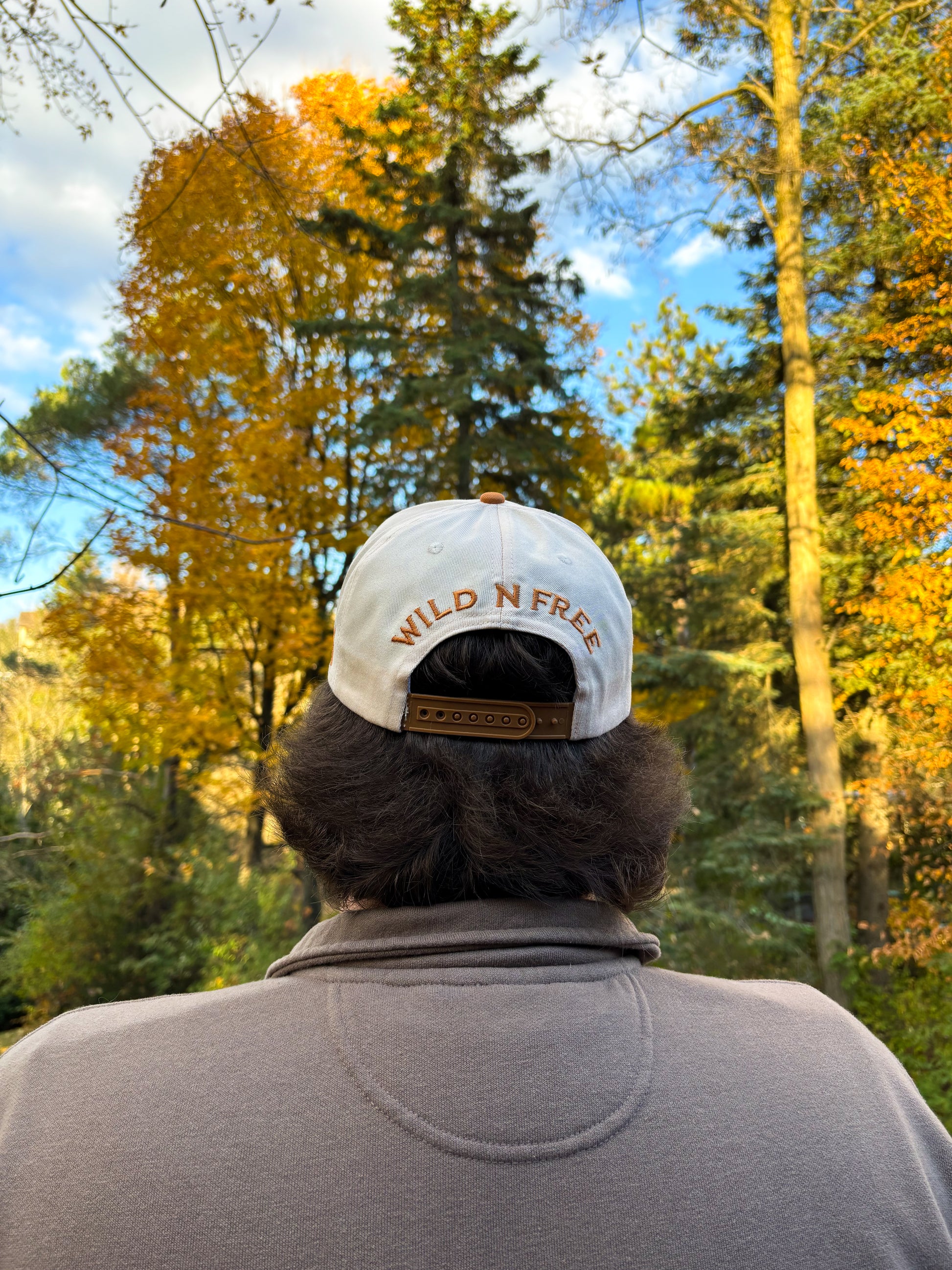 Back view of tan and cream Hides & Kinds Houston Hat with Wild N Free embroidery above the snapback closure.