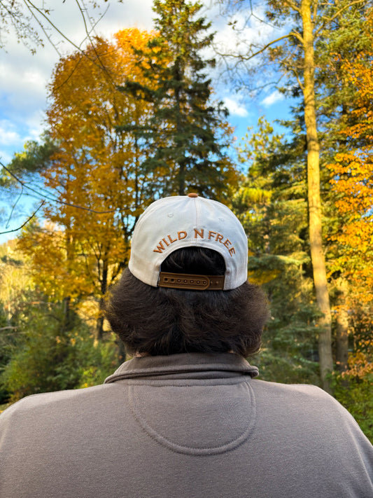 Back view of tan and cream Hides & Kinds Houston Hat with Wild N Free embroidery above the snapback closure.