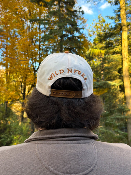Back view of tan and cream Hides & Kinds Houston Hat with Wild N Free embroidery above the snapback closure.