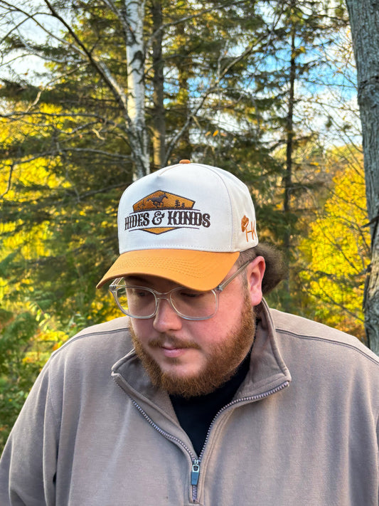 Front view of Hides & Kinds Houston Hat in tan and cream with embroidered desert landscape patch logo.