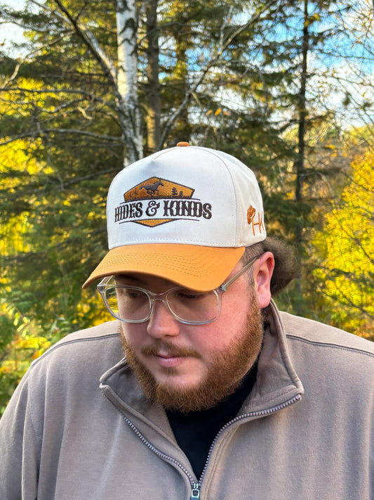Front view of Hides & Kinds Houston Hat in tan and cream with embroidered desert landscape patch logo.