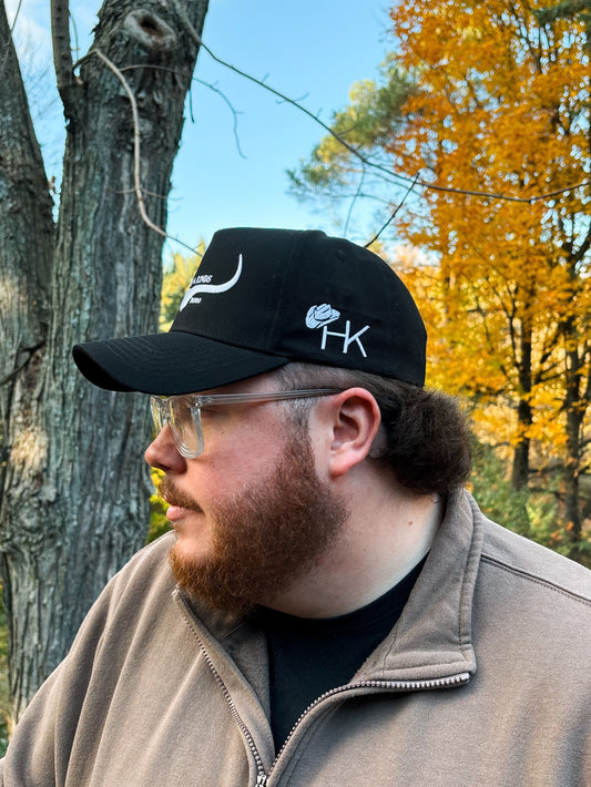 Side profile of black and white Hides & Kinds Original Logo Hat with embroidered HK logo on the side panel.