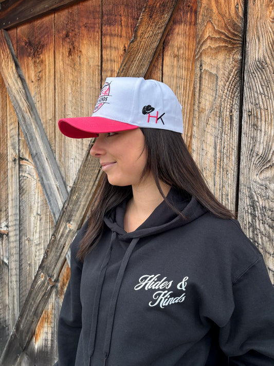 Side profile of Hides & Kinds Stampede Snapback in pink and white featuring HK embroidered hat logo.