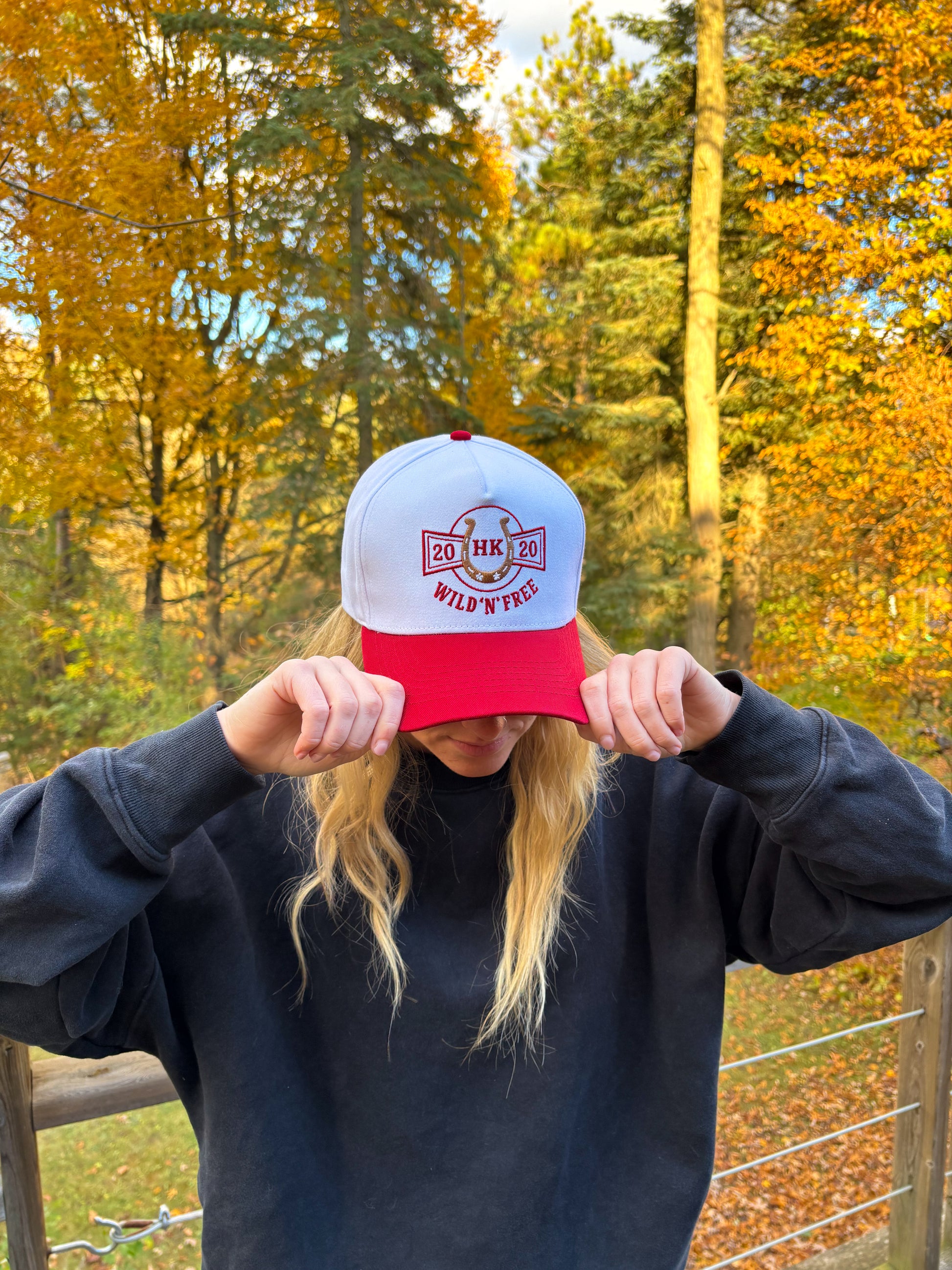 Angled front view of red and white Hides & Kinds Wild N Free Hat showcasing western horseshoe patch design.