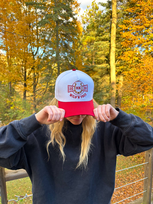 Angled front view of red and white Hides & Kinds Wild N Free Hat showcasing western horseshoe patch design.