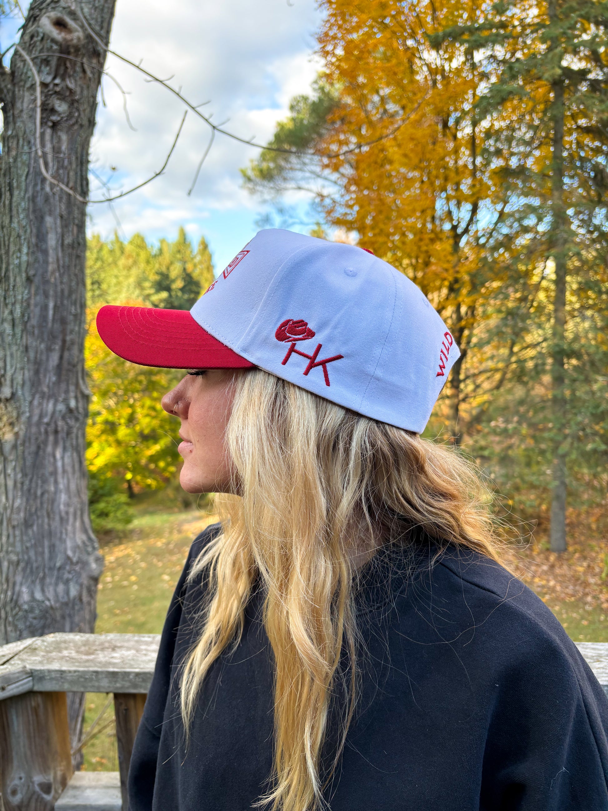 Side profile of red and white Hides & Kinds Wild N Free Hat featuring embroidered HK logo on the side.