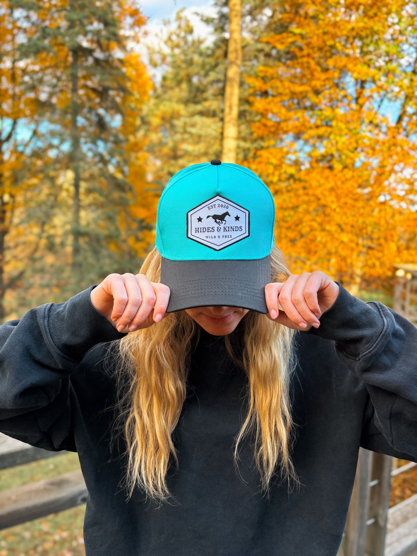 Front view of Hides & Kinds Wild N Free Hat in teal and black with signature logo patch.