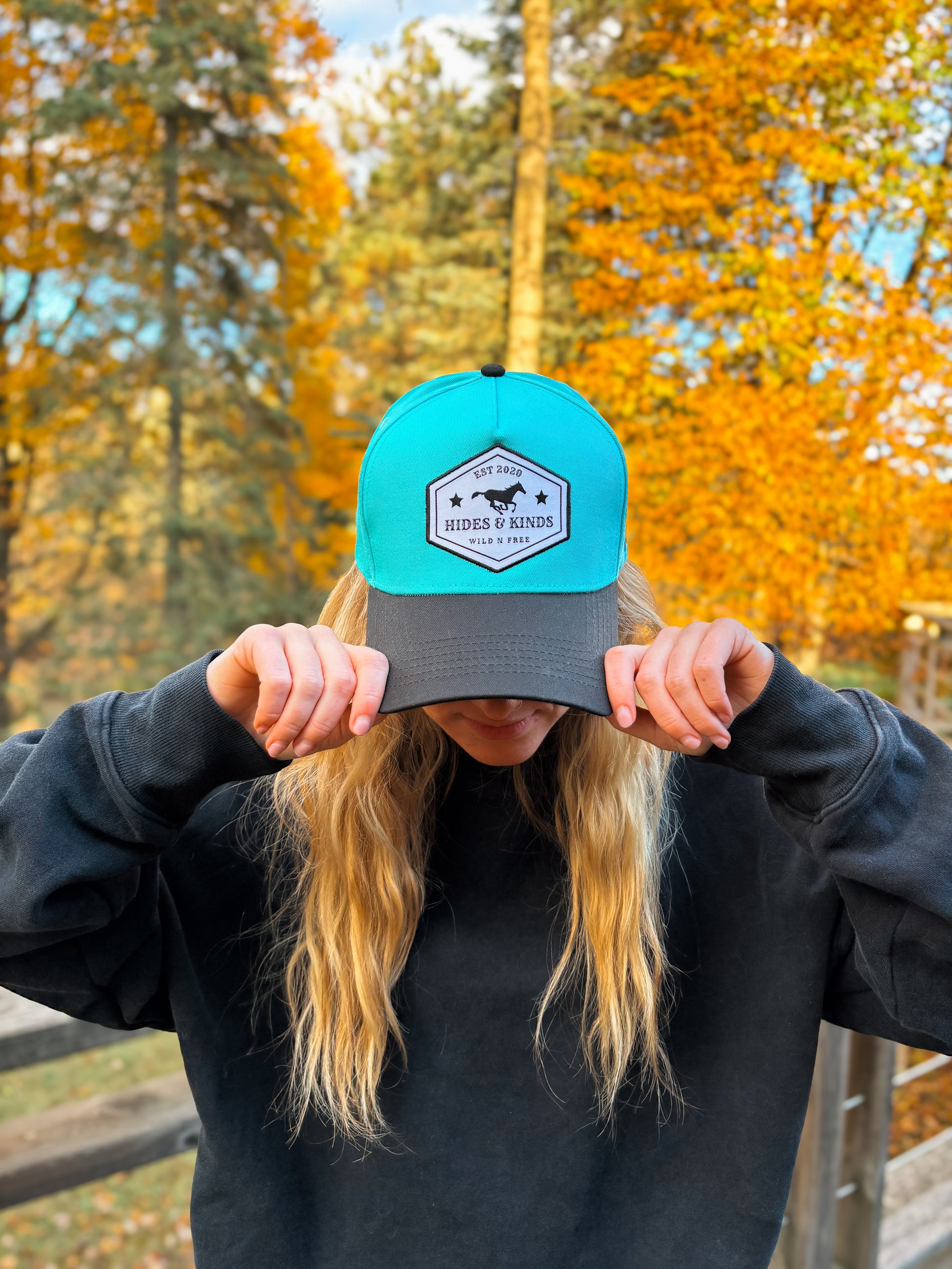 Front view of Hides & Kinds Wild N Free Hat in teal and black with signature logo patch.